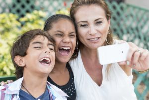 Hispanic mature women posing with her children taking a self photo with her smart phone